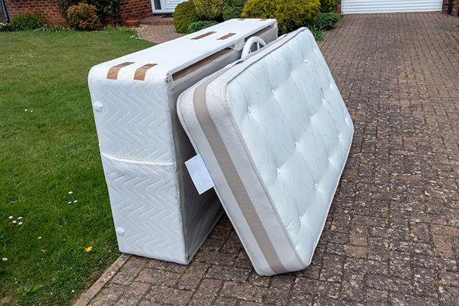 two workers carrying a mattress out of a house